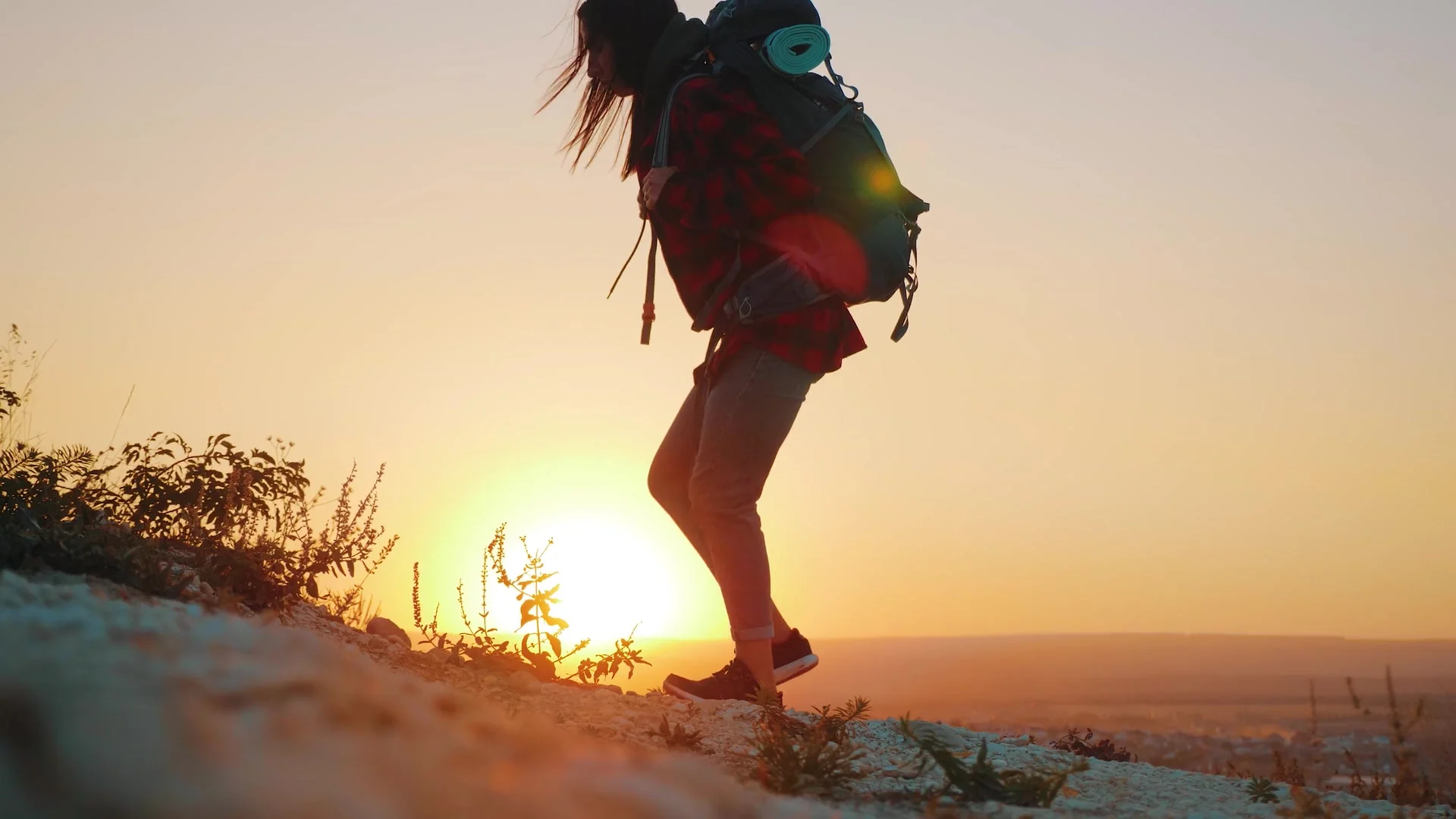 A woman with a backpack hiking in warm evening light