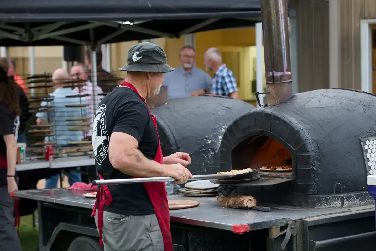 A man cooking pizzas at a Men's Ministry gathering