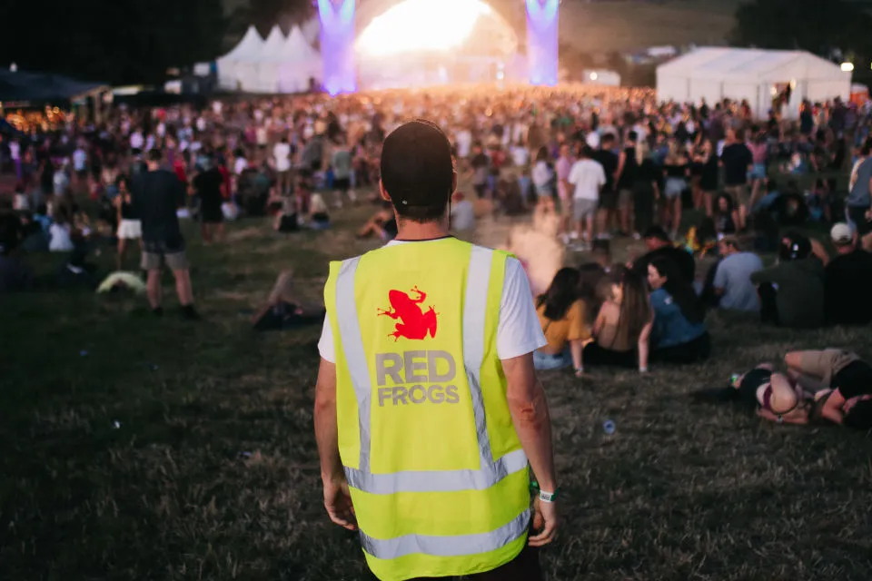 A Red Frogs volunteer in hi-vis overlooking a festival crowd