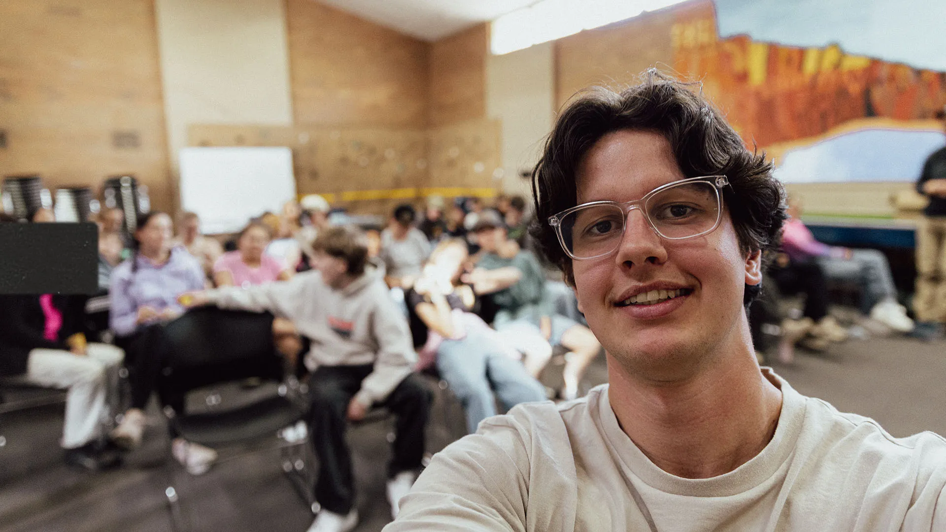A youth leader taking a photo with students in the background